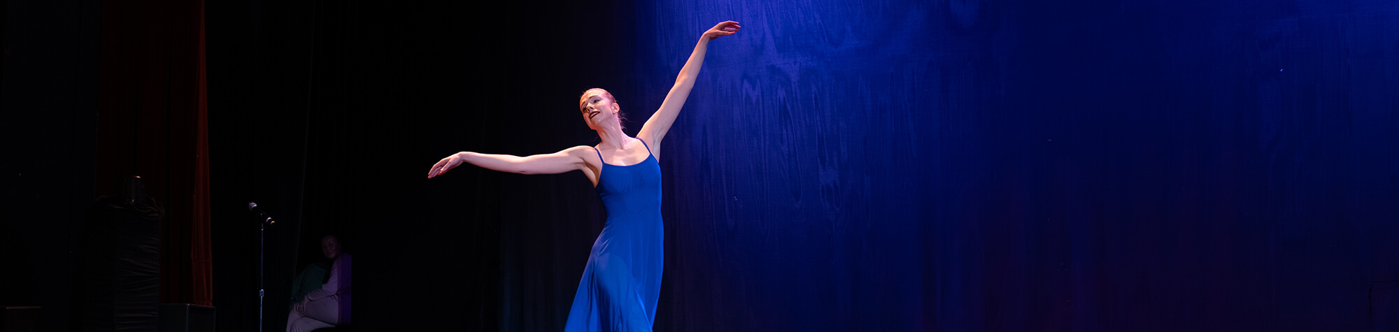 A dancer performs on stage in a blue dress